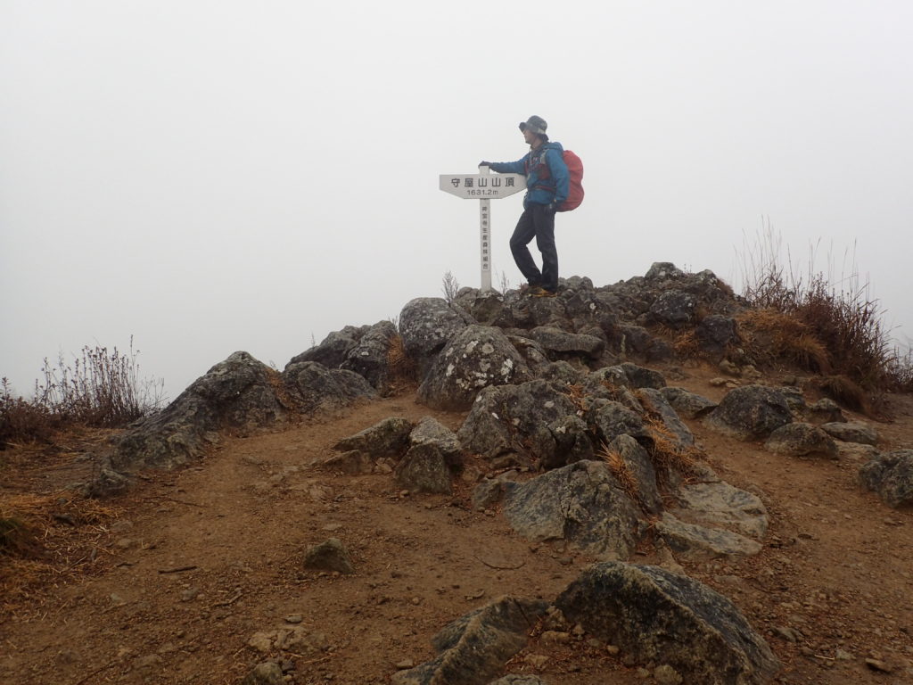 雨の守屋山東峰山頂でモンベルの登山用レインウェアであるトレントフライヤーを着て記念撮影