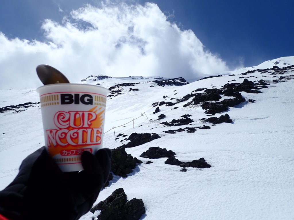 残雪期の富士山で山頂方向を見上げながらのカップラーメン