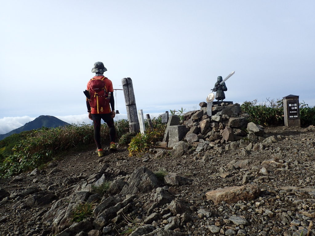 日本百名山である越後駒ヶ岳山頂に立つ背中にモンベルの登山用ザックであるバーサライトパック