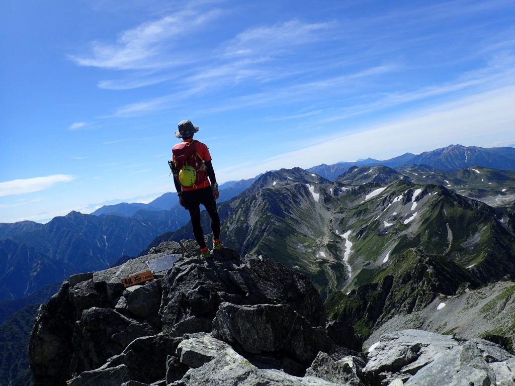 剱岳山頂に立つ背中にモンベルの登山用ザックであるバーサライトパック