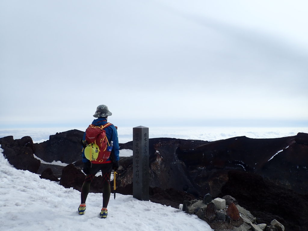 日本最高峰富士山剣ヶ峰山頂でモンベルの登山用レインウェアであるトレントフライヤーを着て記念写真を撮影