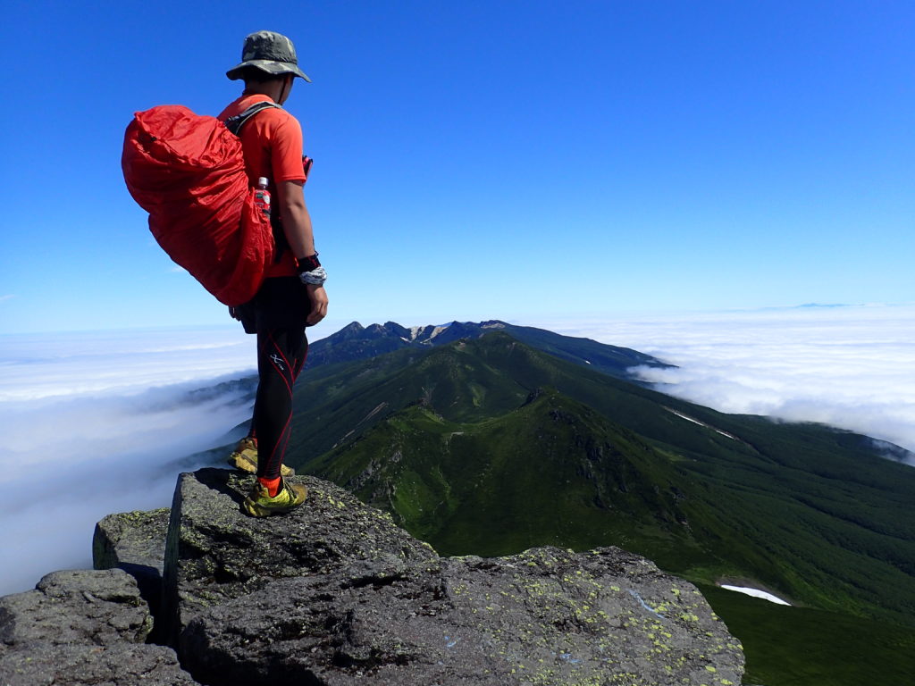 北海道の羅臼岳山頂でザックカバーをかけたザックを背負って記念撮影