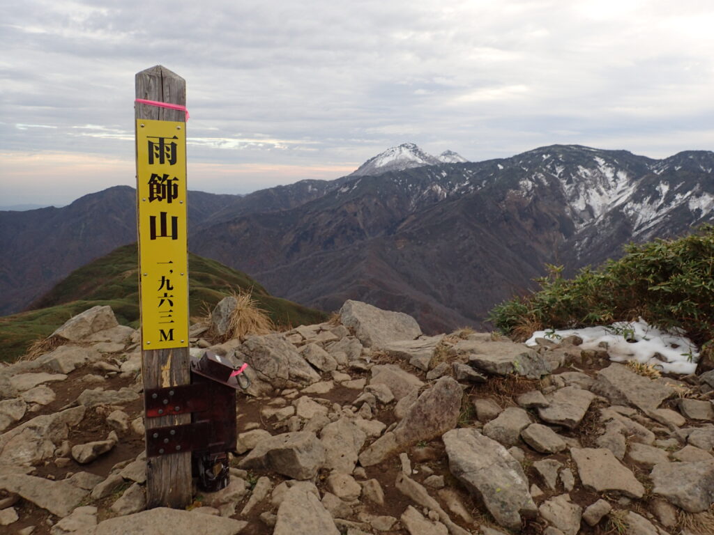 日本百名山の雨飾山を登山した時に撮影した山頂標と雪化粧した北アルプス