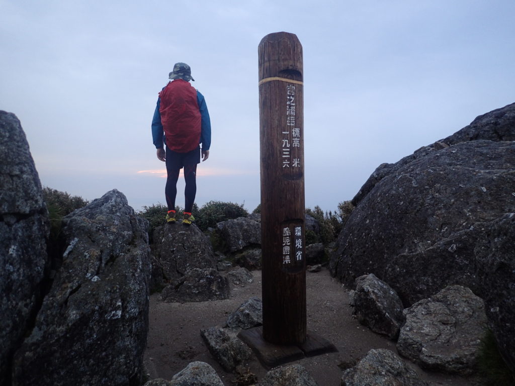 屋久島の宮之浦岳山頂でモンベルの登山用レインウェアであるトレントフライヤーを着て記念撮影