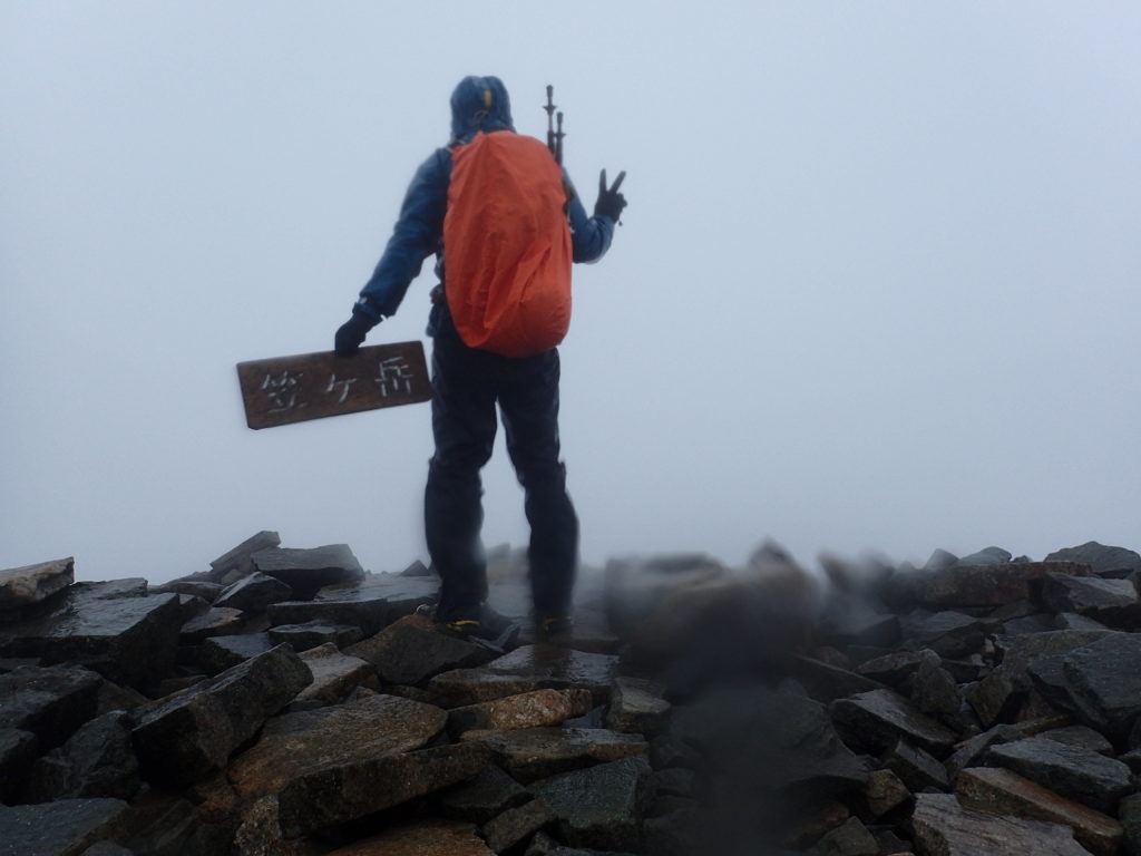 雨の笠ヶ岳山頂でモンベルの登山用レインウェアであるトレントフライヤーを着て記念撮影