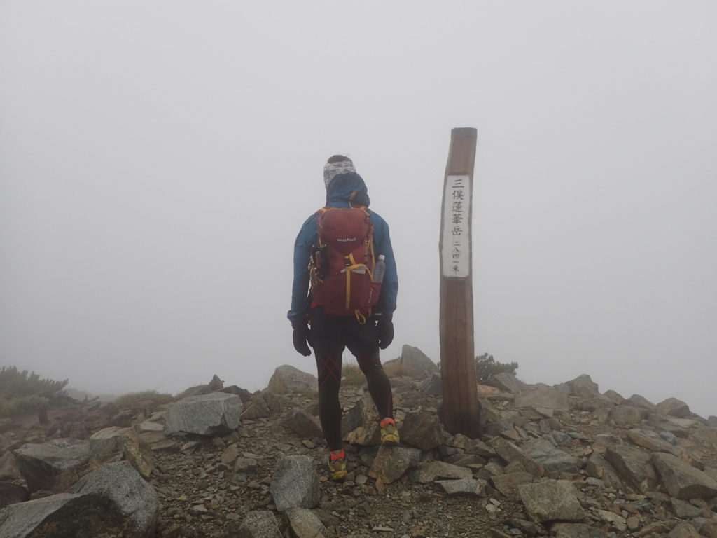 強風の三俣蓮華岳山頂をモンベルの登山用レインウェアであるトレントフライヤーでしのぐ。
