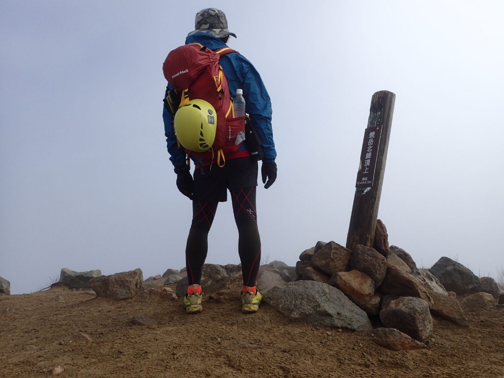焼岳北峰山頂でモンベルの登山用レインウェアであるトレントフライヤージャケットを着て記念撮影