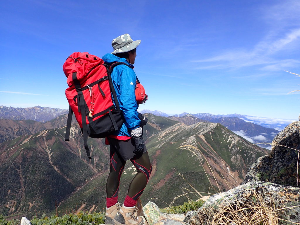 常念岳山頂でモンベルの登山用レインウェアであるトレントフライヤージャケットを着て記念撮影