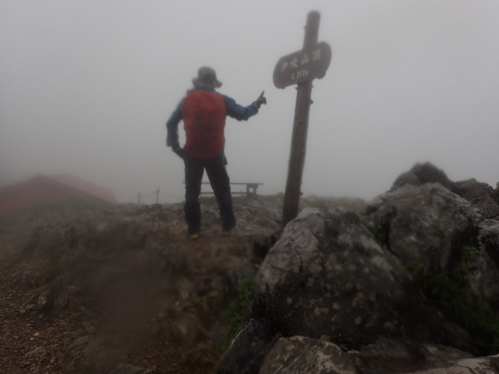 雨の伊吹山山頂でモンベルの登山用レインウェアであるトレントフライヤーを着て記念撮影