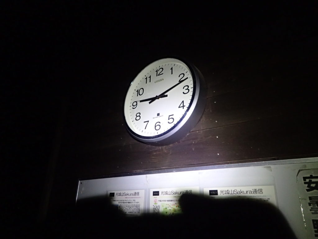 午後9時の光城山山頂無料休憩所の時計をブラックダイヤモンドの登山用ヘッドライトであるストームの灯りで照らす