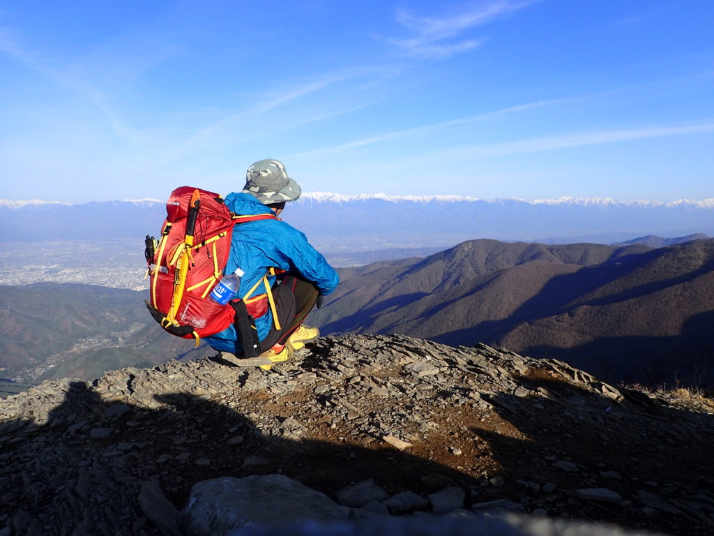 美ヶ原の王ヶ鼻で北アルプスを背景にモンベルの登山用レインウェアであるトレントフライーを着て記念撮影