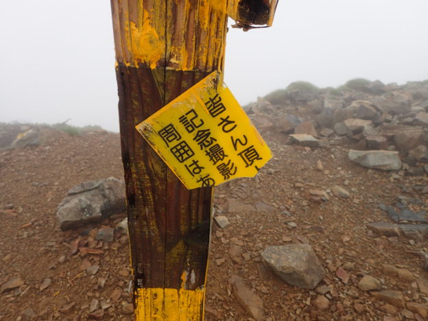 山頂標は登山者が記念撮影をする場所なので、周囲はあけるのがマナーであることを喚起している北アルプスの鹿島槍ヶ岳山頂のメッセージ