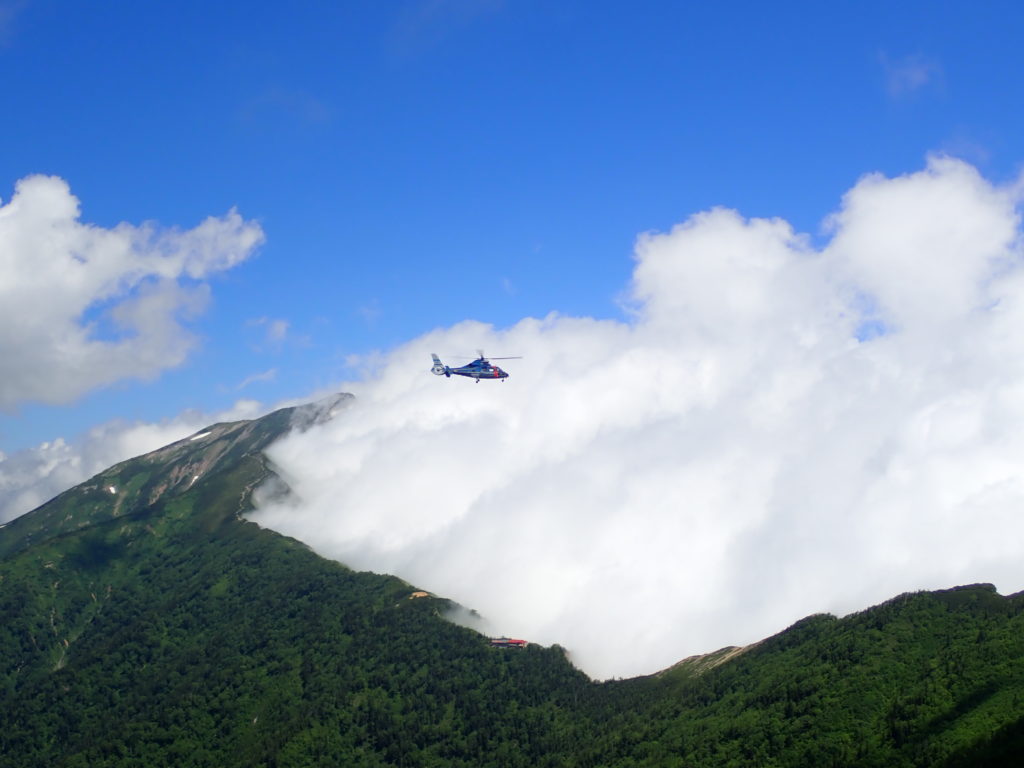 北アルプスの爺ヶ岳と鹿島槍ヶ岳登山をした時に撮影した雲をせき止めている稜線とヘリコプター